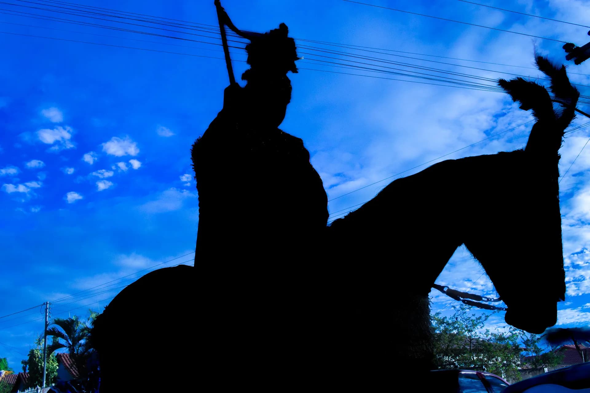 A rider in plumed helmet silhouetted against a blue sky, lance raised.