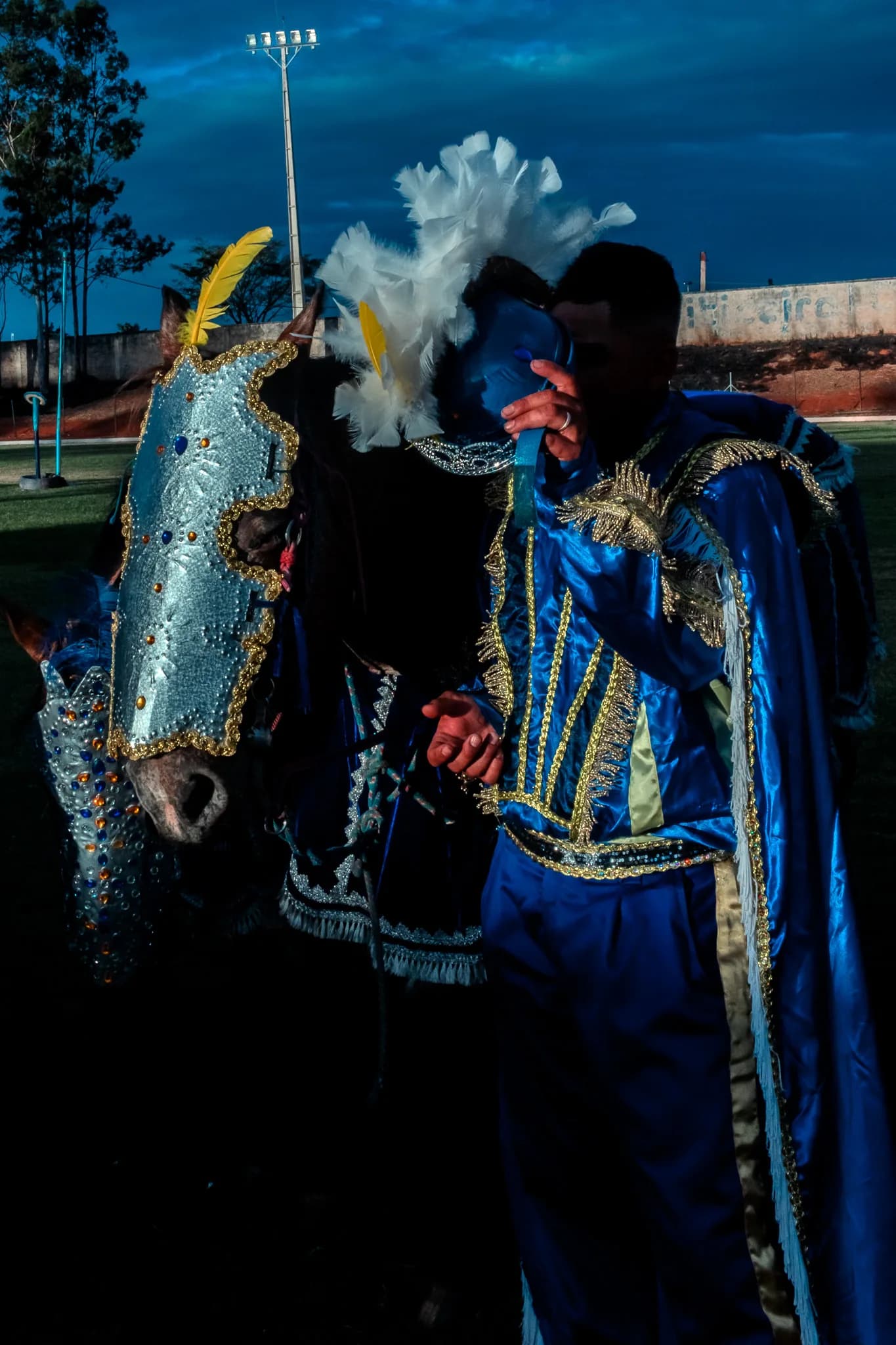 The same blue rider on foot, beside the decorated horse.
