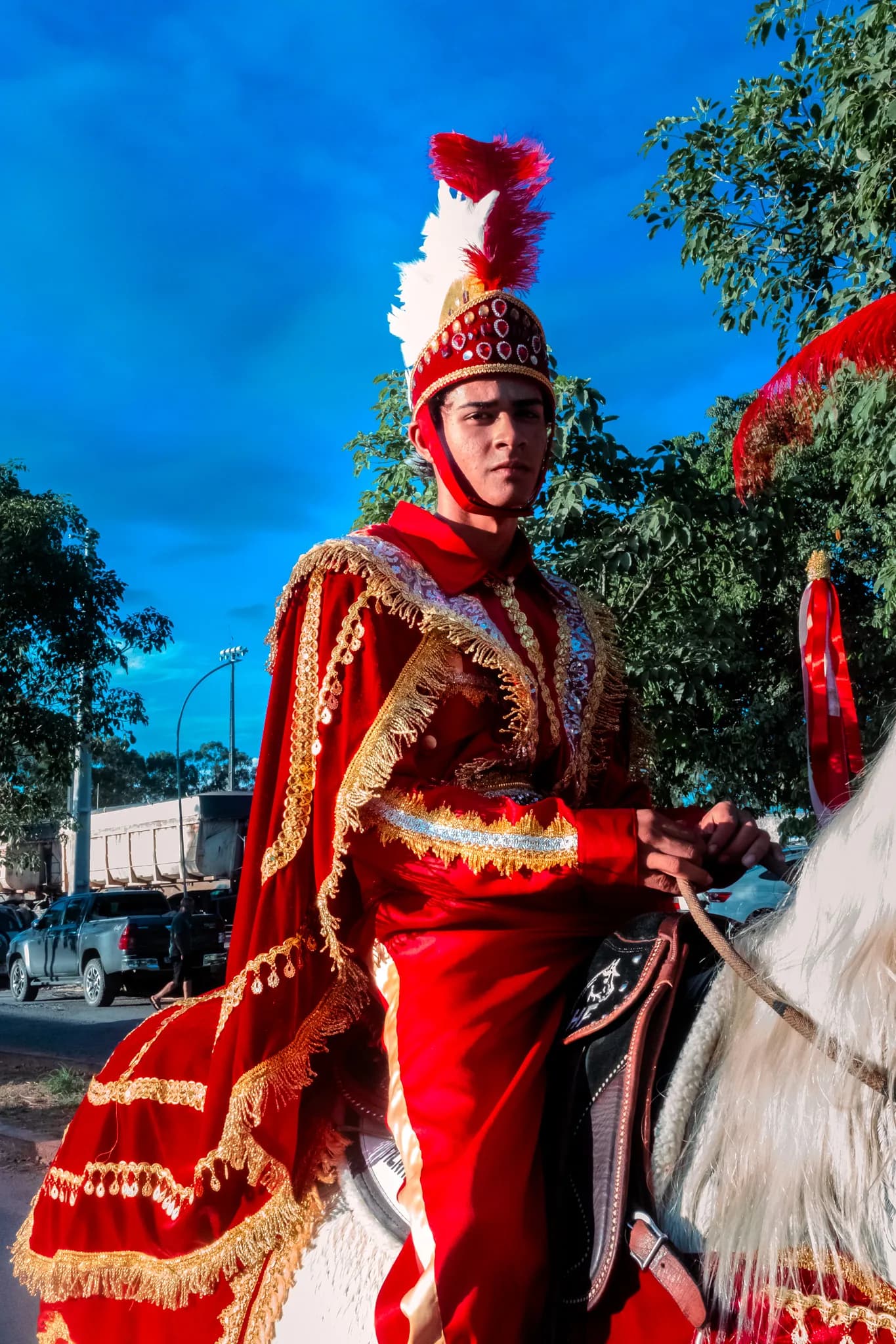 A Christian rider in red and gold on a white horse, seen from the front.