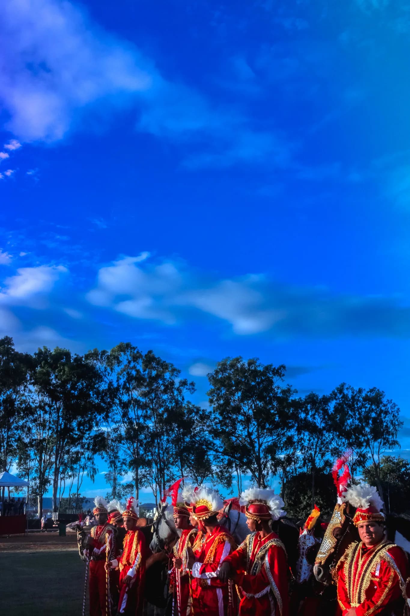 The procession of riders under a wide blue sky at the end of the day.