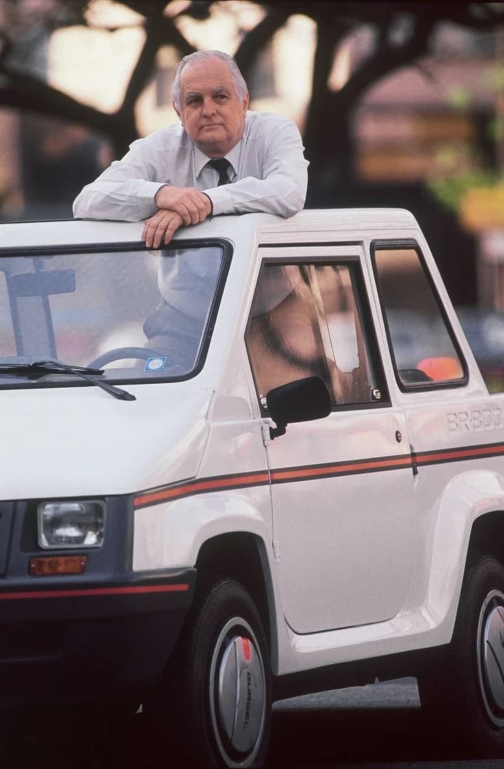 Joao Augusto Conrado do Amaral Gurgel leaning on the open door of a Gurgel Supermini.