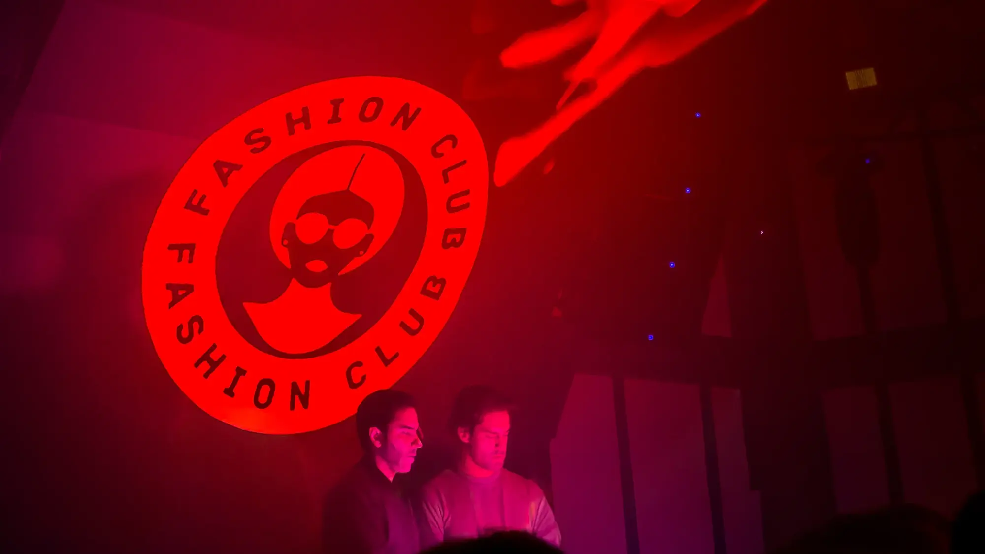 Two DJs under a lit Fashion Club logo at a Runway Untd night