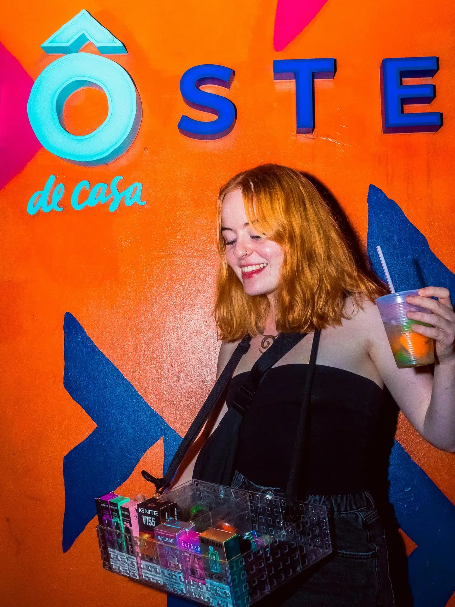 A guest walking past the orange Ô de Casa mural holding a drink.