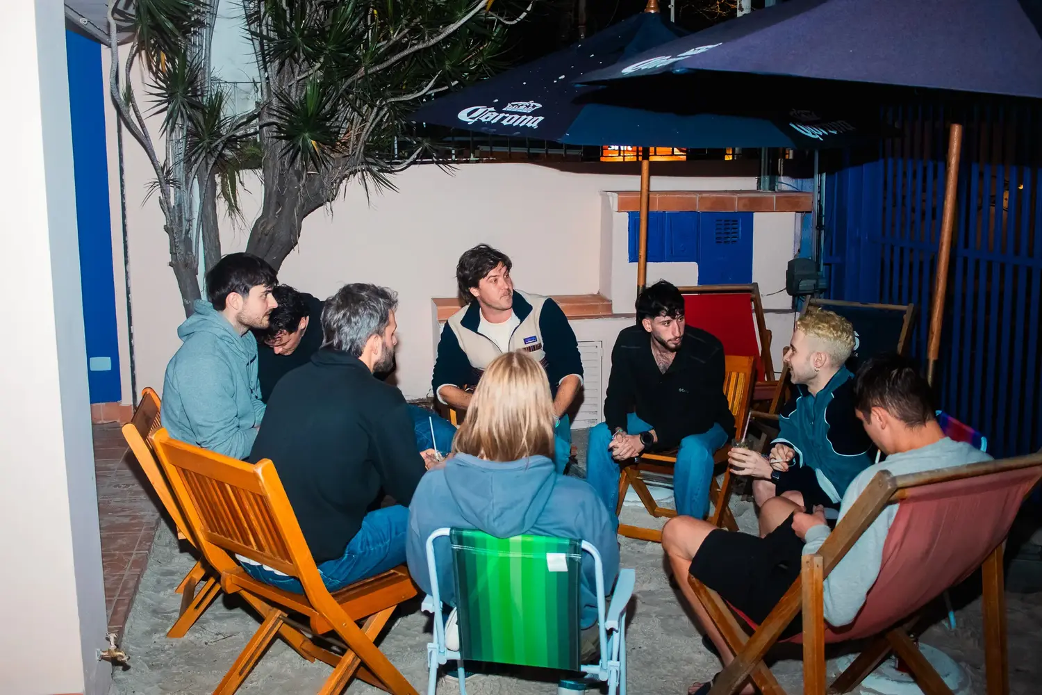 Guests seated in deck chairs in the outdoor area under an umbrella.