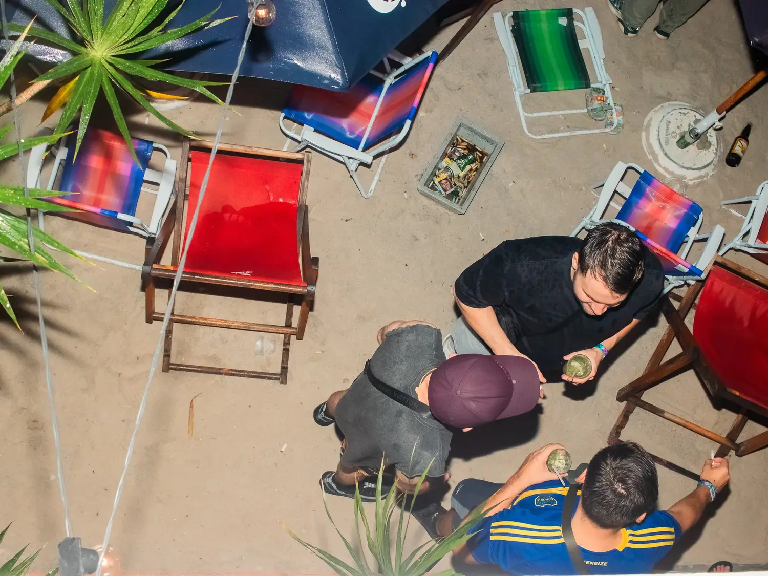 The outdoor deck seen from above, coloured chairs and guests around a table.