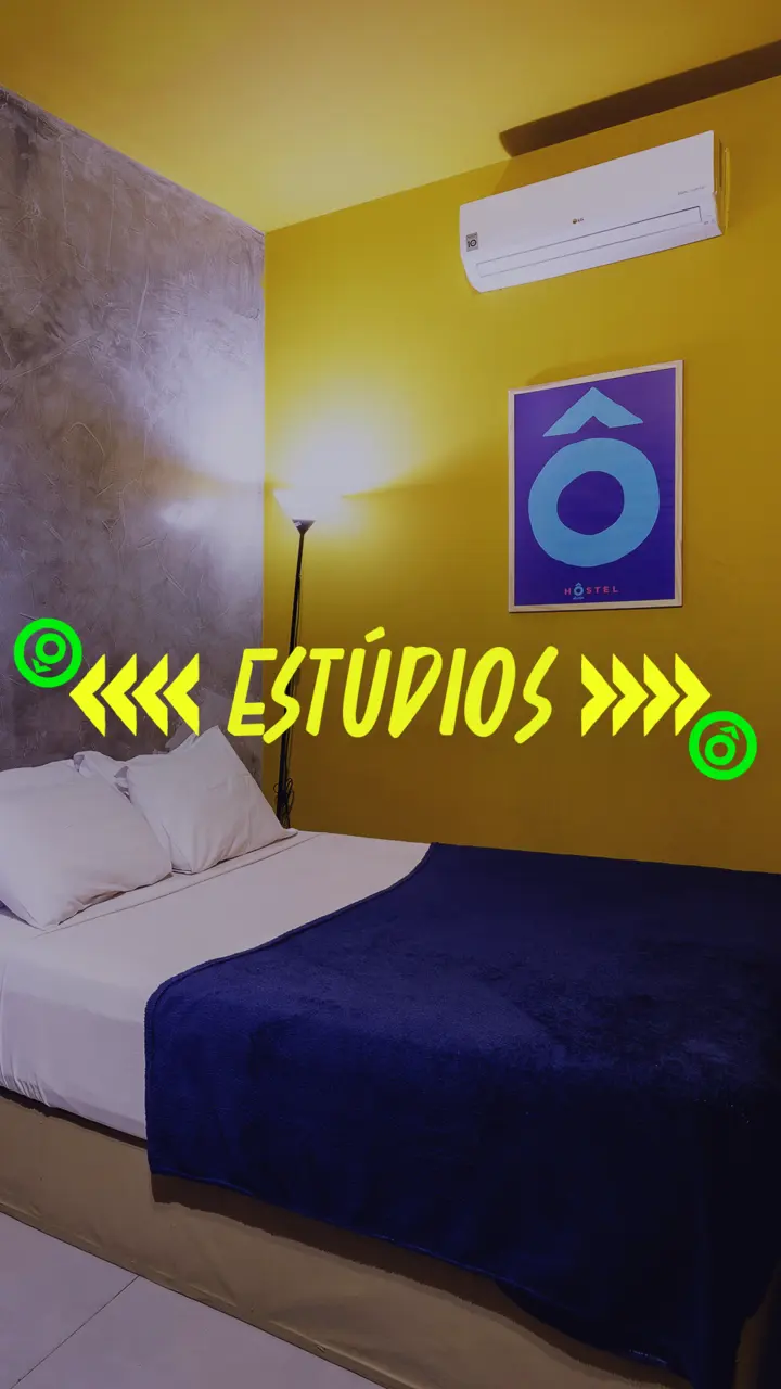 A studio with a double bed and yellow wall.